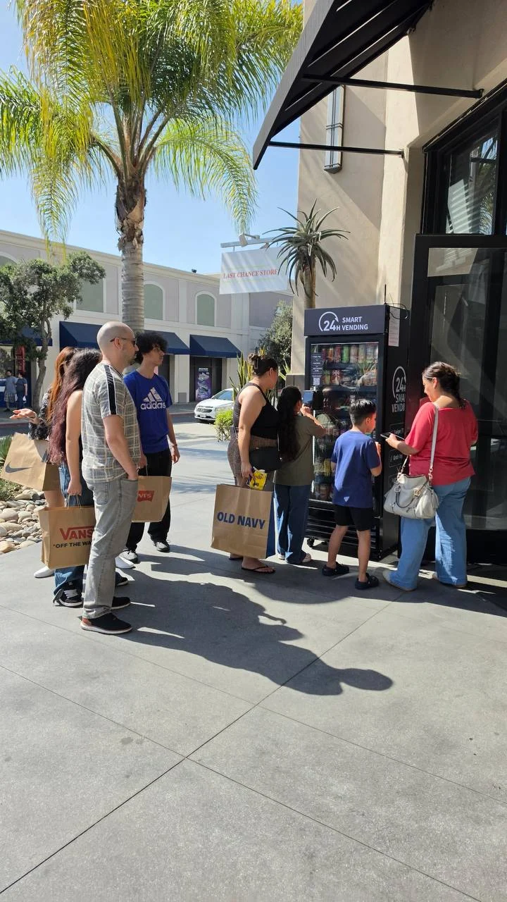 People gathering to grab snacks and drinks from a Smart Bites smart cooler